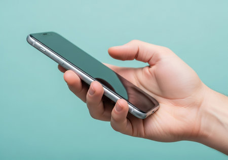 Smartphone in hand on turquoise background. Close-up.の写真素材