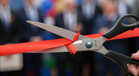 Businessman cutting red ribbon with scissors on blurred background, closeupの写真素材