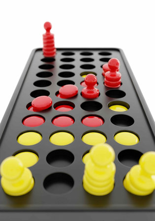 Red and yellow game pieces on a black board isolated on white backgroundの写真素材