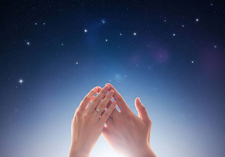 Hands of woman praying against starry night sky in the backgroundの写真素材