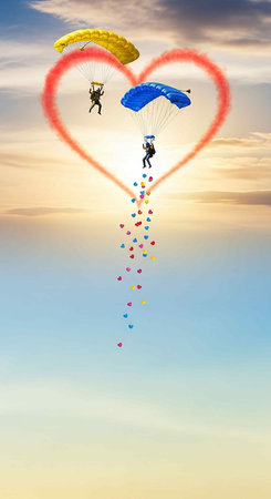 Parachutist flying in the sky with heart-shaped cloudsの写真素材