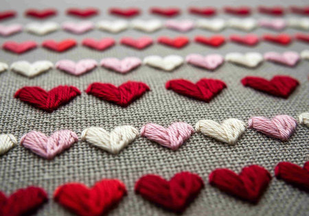Colorful heart embroidery on fabric background. Red, pink and white hearts.