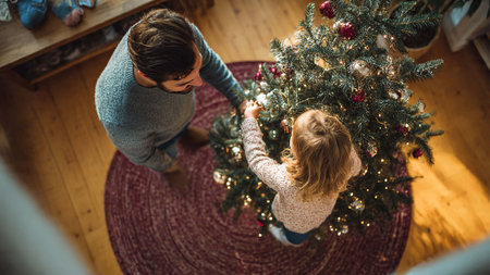 Top view of father and daughter decorating christmas tree at homeの写真素材