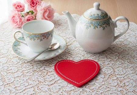 Cup of tea, teapot and red heart on lace tableclothの写真素材
