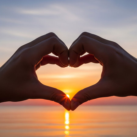 Silhouette of hands forming a heart shape on the sunset backgroundの写真素材