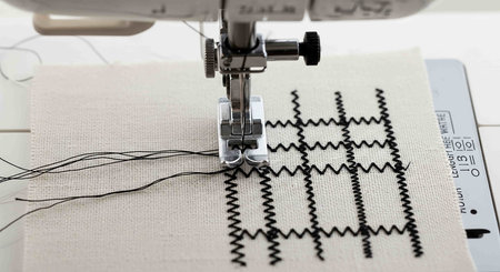 Sewing machine and thread on fabric, close-up view