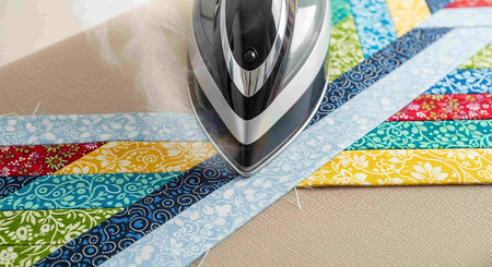 Iron on the ironing board with a pattern of colorful fabrics.