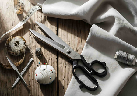 Sewing tools on a wooden table. Scissors, thread, pins and measuring tape.