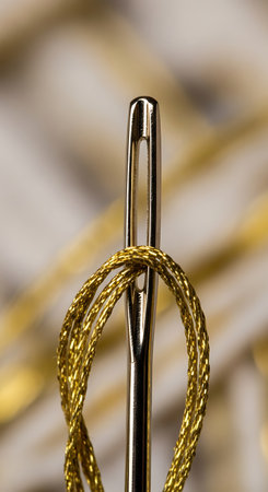 Close-up of a needle with a yellow thread on a white backgroundの写真素材