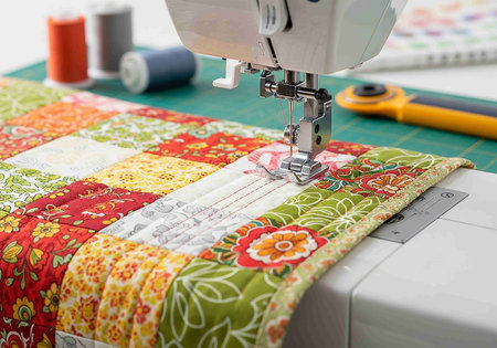 Sewing machine and patchwork quilt on a white background