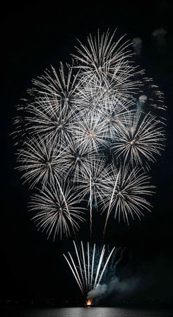 Colorful fireworks of various colors over night sky with reflection on water