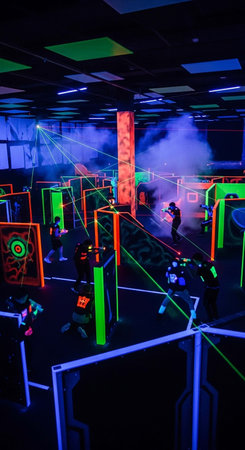 Unidentified people play laser tag game in a dark room. Modern entertainment industry.