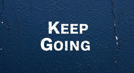 Keep Going sign on blue painted wall. Motivational background.の写真素材