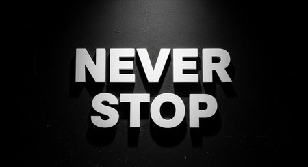 Never stop sign on a black wall. Motivational background.の写真素材