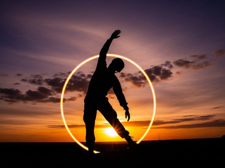 Silhouette of a young man dancing on a sunset background.の写真素材