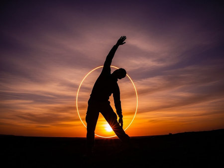 Silhouette of a man practicing yoga on the sunset background.の写真素材