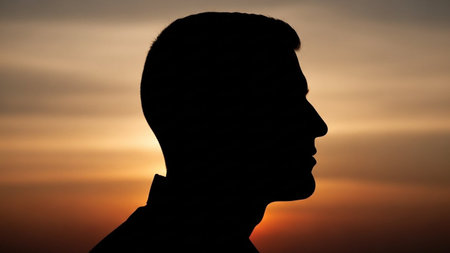 Silhouette of a man in profile against a sunset background.の写真素材
