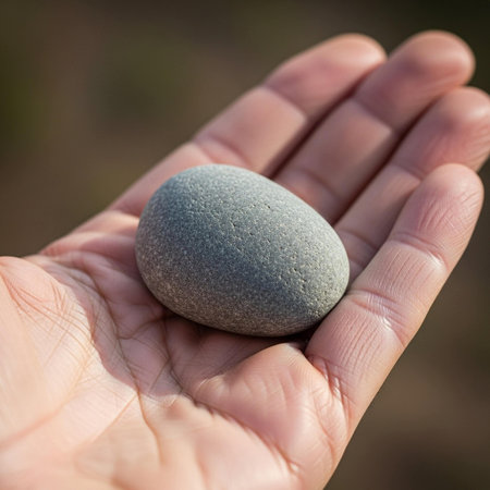 Hand holding a stone on a blurred background. Shallow depth of field.の写真素材