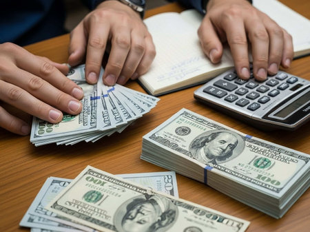 Hands counting money on table with calculator and notebook, business concept