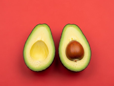 Avocado fruit isolated on red background. Half of avocado with seed