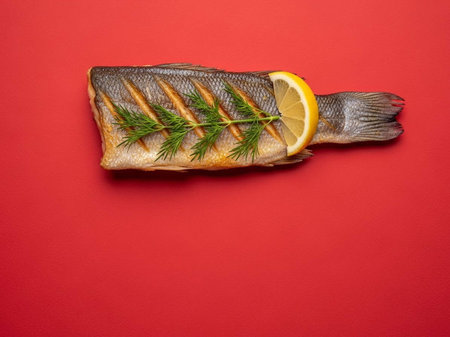 Roasted fish with lemon and dill on a red background.の写真素材
