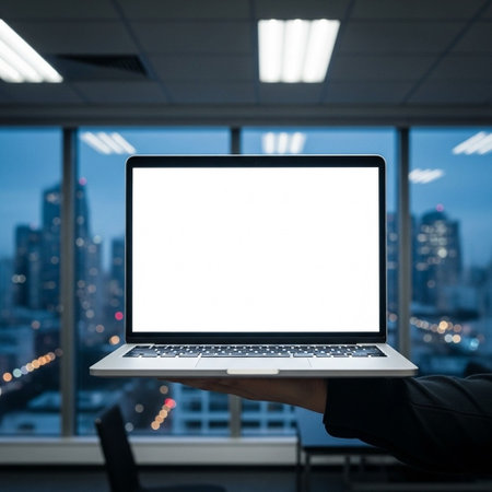 Businessman holding laptop with blank screen in office with cityscape background.の写真素材