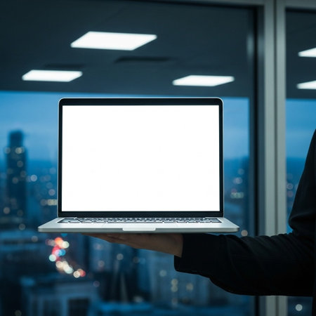 Businessman hand holding laptop with blank screen on blurred cityscape backgroundの写真素材