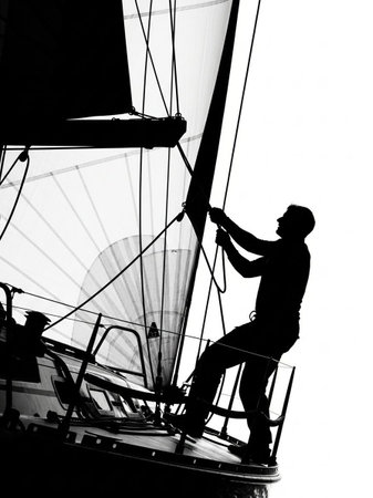 Silhouette of a man on a sailboat. Black and white.
