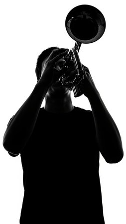 one caucasian young man playing trumpet silhouette in studio isolated on white backgroundの写真素材