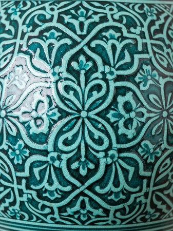 A close-up view of an intricately designed teal ceramic vase with floral patternsの写真素材