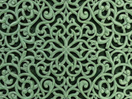 Intricate green metalwork pattern with ornate swirling designs and symmetrical floral motifsの写真素材
