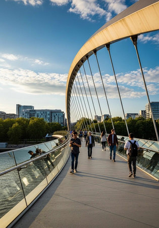 People walking on a modern bridge with a stunning cityscape and blue sky in the background