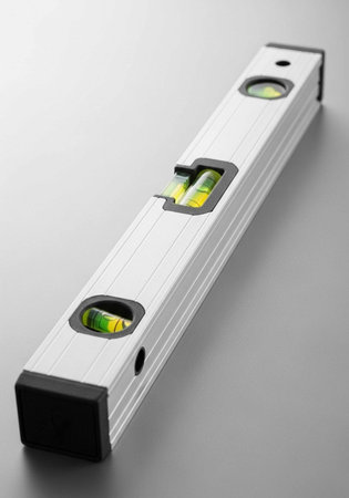 A silver level tool with black accents and green bubble levels on a gray surface