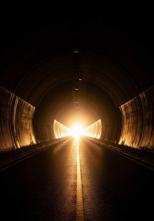 A dark tunnel with a bright light at the end, leading to a hopeful exitの写真素材