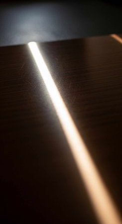 A single ray of sunlight illuminates a dark wooden surface, creating a stark contrast.の写真素材