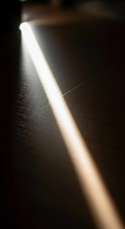 A single, intense light beam shining on a dark, smooth surface.
