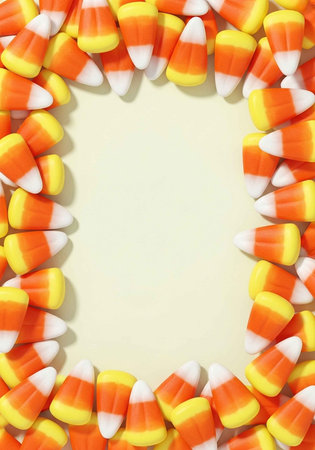 A colorful border of candy corn on a pale yellow backgroundの写真素材