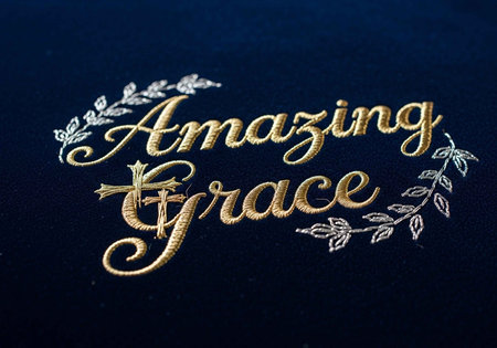 Intricate gold and silver embroidery of "Amazing Grace" on dark fabric with leafy accents.の写真素材