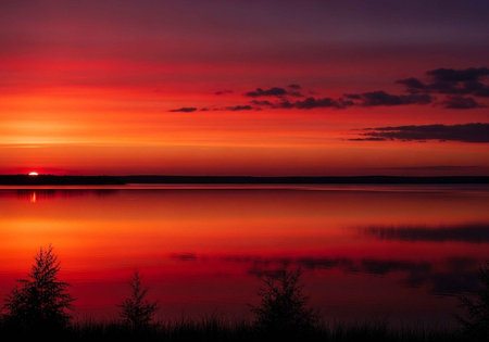 A serene lake at sunset with vibrant colors in the skyの写真素材