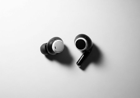 A pair of sleek black wireless earbuds on a white surface