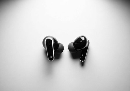 A pair of sleek black wireless earbuds on a white surface