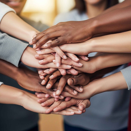 A group of diverse people stacking their hands together in unity and solidarity