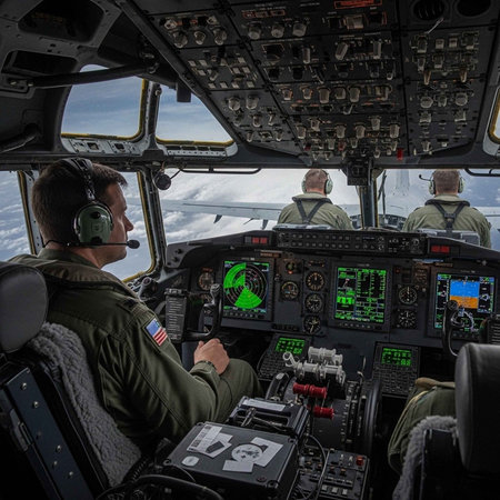 Military pilots in the cockpit of an aircraft flying through cloudy skies