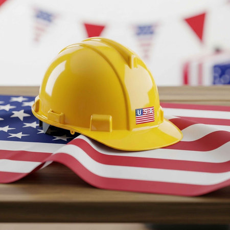 A yellow hard hat with an American flag sticker on a USA flagの写真素材