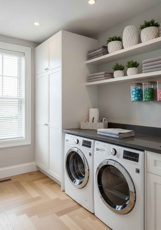 A modern laundry room with white cabinets and a washer and dryerの写真素材