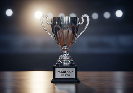 A shiny silver trophy cup on a wooden table with a runner-up second place plaque
