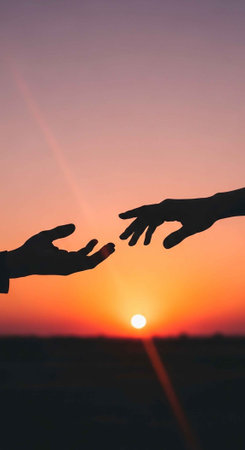 Two hands reaching out to each other in a beautiful sunset landscape