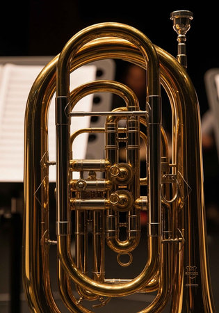 Detailed view of a shiny brass euphonium with visible valves and tubing, sheet music in the background.の写真素材