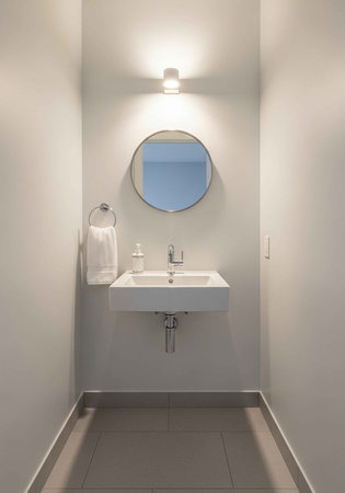 A modern bathroom with a sleek white sink and round mirror on the wall