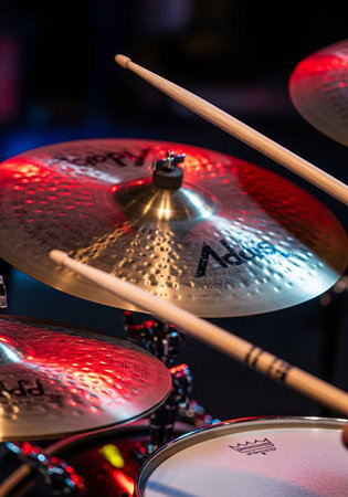 A close-up view of a drum set with cymbals and drumsticks in a dark roomの写真素材